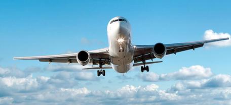 Großes Passagierflugzeug mit ausgefahrenem Fahrwerk im Landeanflug vor blauem Himmel.