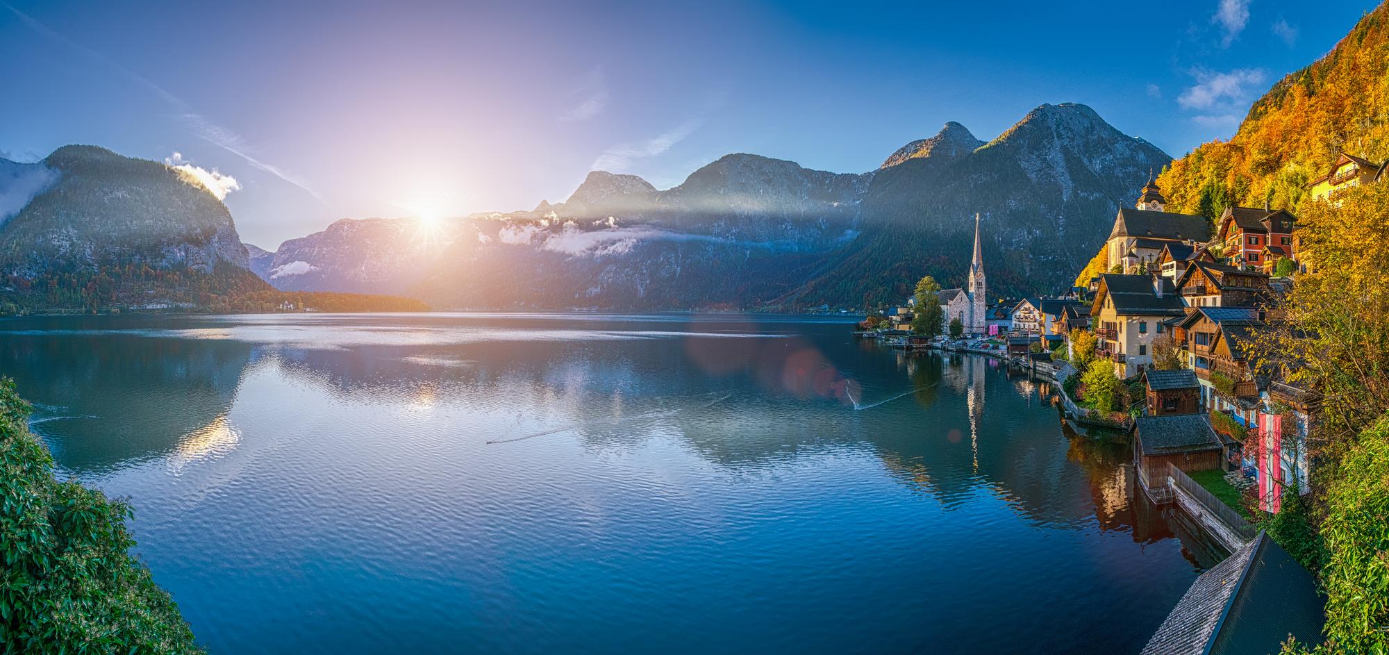 Picturesque lake landscape with mountains and village at sunrise.