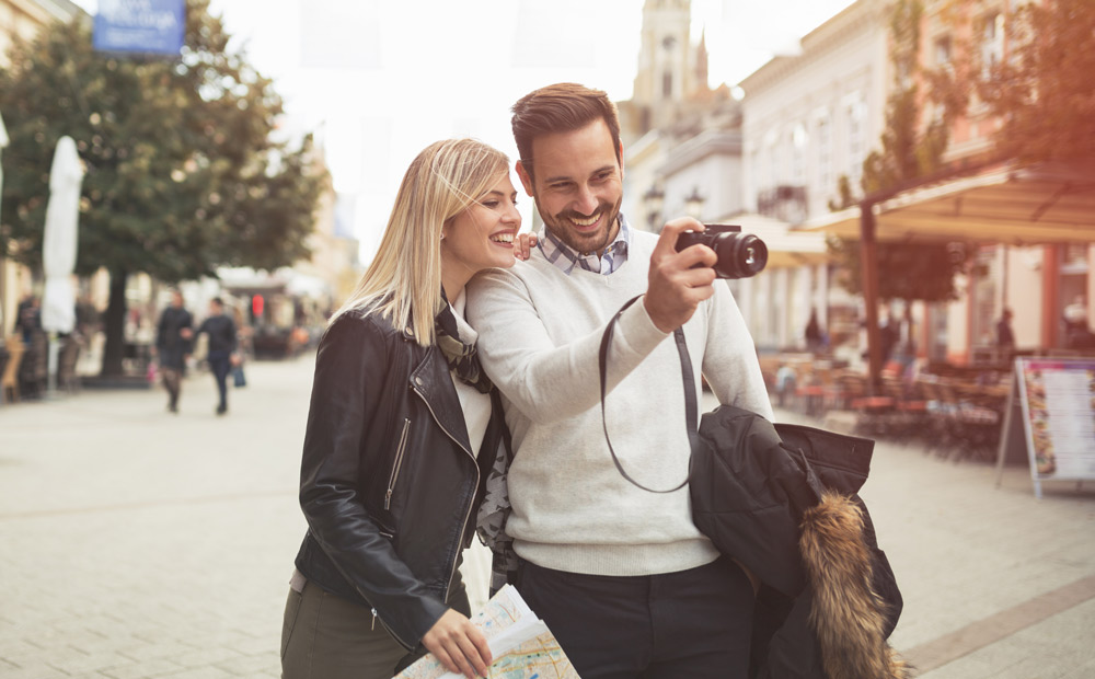 Two casually dressed people taking photos in an urban setting &ndash; a moment full of discoveries.