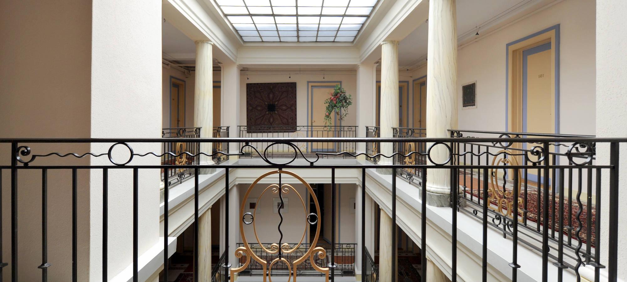 Helles Atrium mit Säulen und verzierten schwarzen Geländern