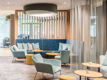 Moderne Lounge mit Sesseln, Sofas und runden Tischen in hellen Farben.