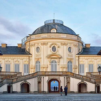 Solitude Palace in Stuttgart with baroque facade, staircase, and clear sky.