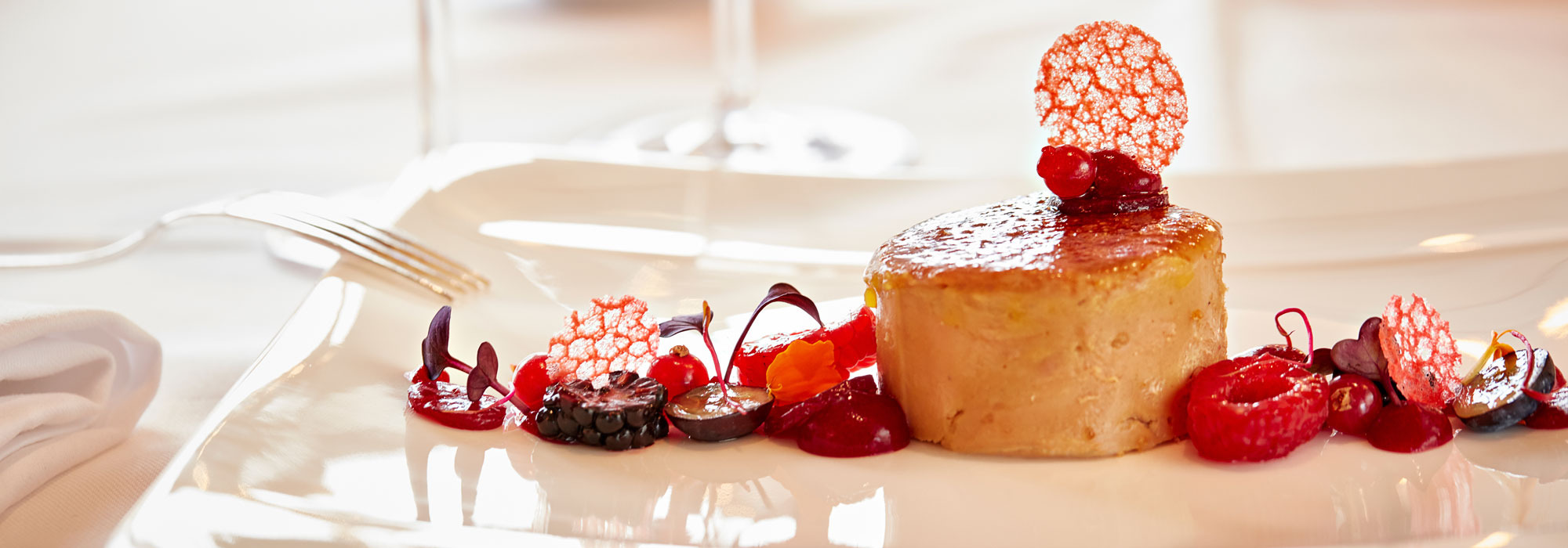 Fein angerichtetes Dessert mit Beeren und knusprigen Dekorelementen