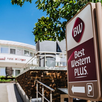 Außenansicht des modernen Best Western Plus Hotels in Willingen mit Logo, großen Fenstern und grüner Umgebung bei klarem Himmel.