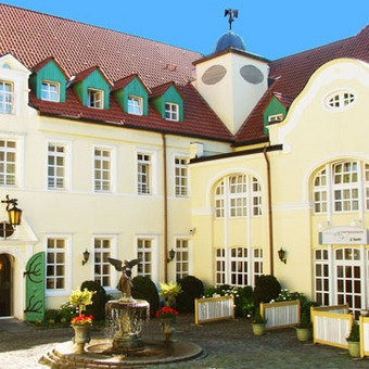 Historic building with a clock tower, green shutters, and a red tiled roof – a charming example of regional architecture, perfect as a setting for a heritage-style hotel.