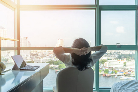 Person looks out at city skyline, with laptop and globe on desk – symbolizing business trip planning.