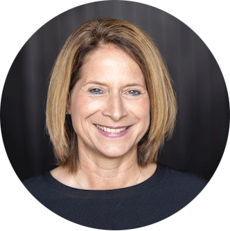 Sabine D&auml;chert mit kurzem, hellem Haar l&auml;chelt vor dunklem Hintergrund in rundem Bildausschnitt