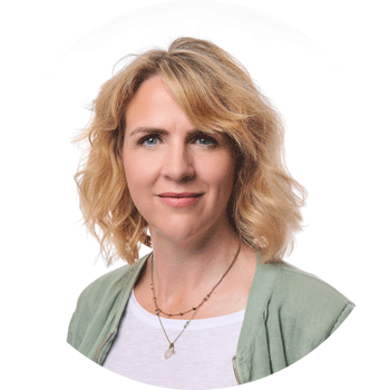 Julia Gruber mit lockigem Haar und gr&uuml;ner Jacke, freundlicher Ausdruck.