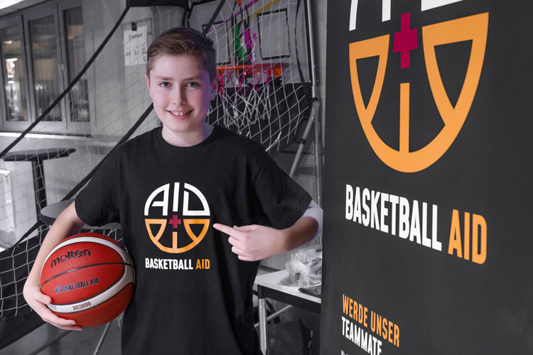 Person mit Basketball und &bdquo;Basketball Aid&ldquo;-Logo bei Charity-Event