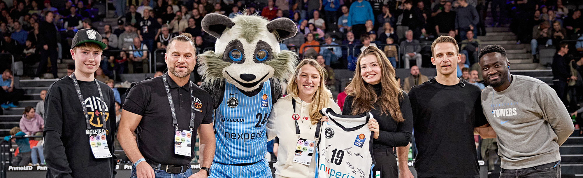 Basketball-Maskottchen mit Fans und Trikot bei einem Spiel in der Arena