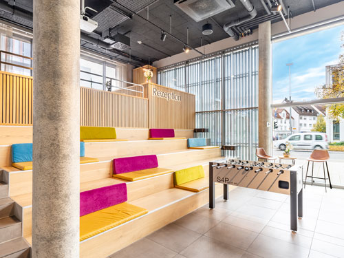 Moderne Hotellobby mit bunten Sitzstufen und Kickertisch.