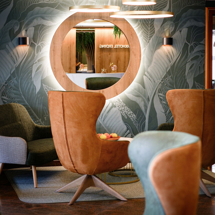 Moderner Loungebereich mit runden Spiegeln und eleganten Sesseln.