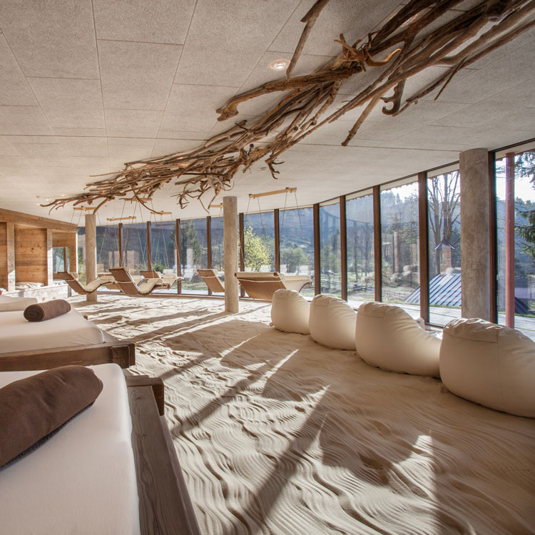 Entspannungsraum mit Sandboden, Liegen und Panoramafenstern.