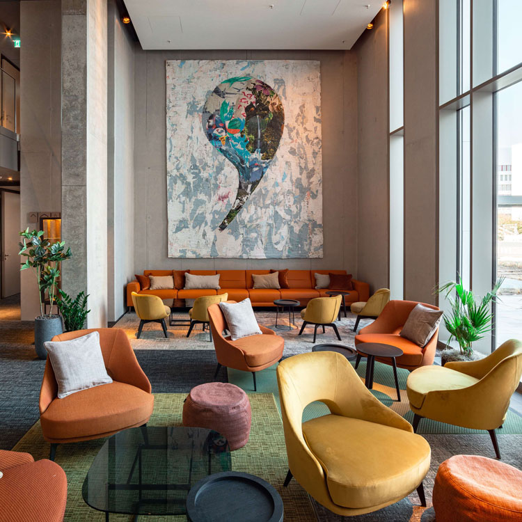 Moderne Hotellobby mit bunten Sesseln und gro&szlig;em abstraktem Kunstwerk.
