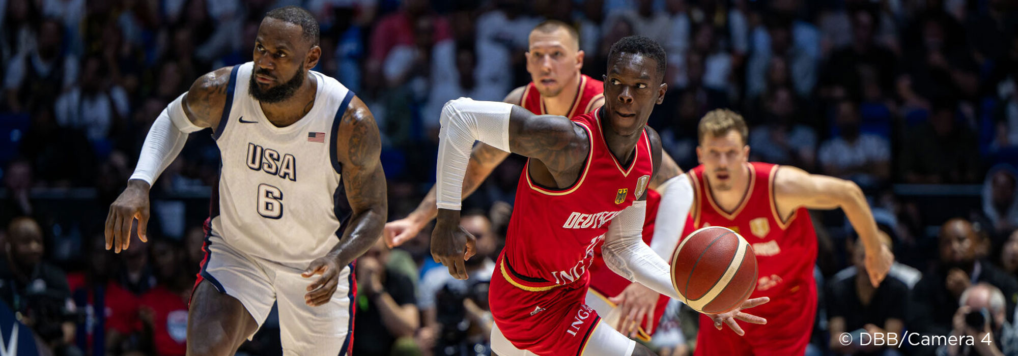 German player dribbles against USA player during basketball match.