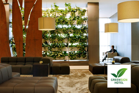 Moderne Hotellobby mit grüner Pflanzenwand und Greensign-Logo.