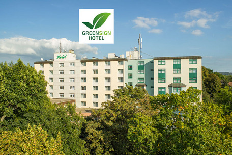 Hotelgebäude umgeben von Bäumen mit Greensign-Logo.