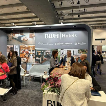 BWH Hotels booth with tables, seating areas, and informational materials.