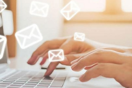 Close-up of hands typing on a keyboard, with sunlight through a window in the background – symbolizes digital communication.