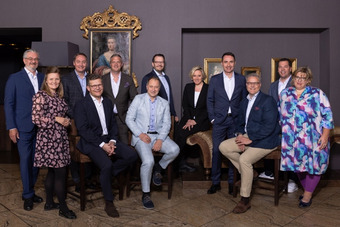 Group photo of the BWH Hotels advisory board and management: twelve people in business attire seated and standing in an elegant room with paintings and an ornate frame.