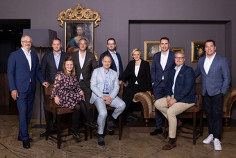 Group photo of the BWH Hotels advisory board: ten people in business attire seated and standing in an elegant room with paintings and ornate frame.