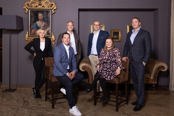 Group photo of the DEHAG supervisory board: six people in business attire seated and standing in an elegant room with paintings and an ornate frame.