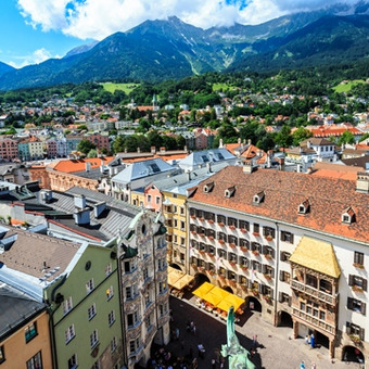 Bunte Altstadt in Innsbruck mit goldenem Dach vor grüner Bergkulisse.