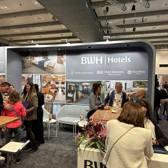 Messestand von BWH Hotels mit Tischen, Sitzgelegenheiten und Infomaterialien.